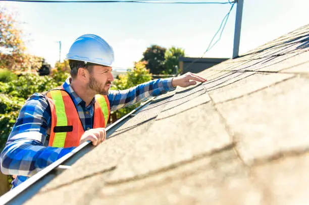 A professional roofer conducting a detailed roof inspection on a house in Pflugerville, TX