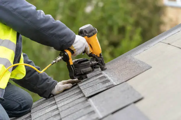 A professional roofer is installing shingles on a residential roof with precision in Pflugerville