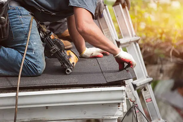 A skilled roofer repairing damaged shingles on a residential roof in in Pflugerville